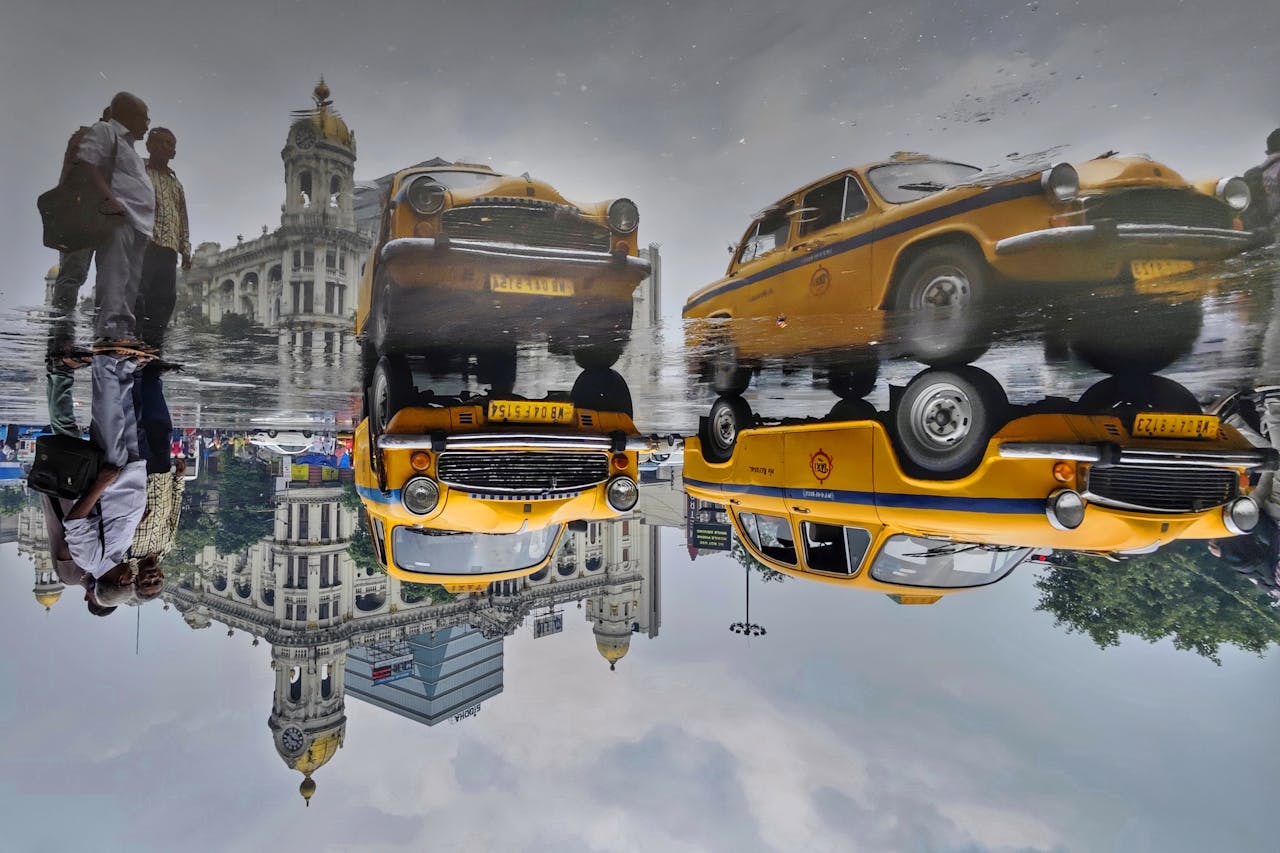 Rainy day in Kolkata with iconic yellow taxis reflecting on wet pavement.